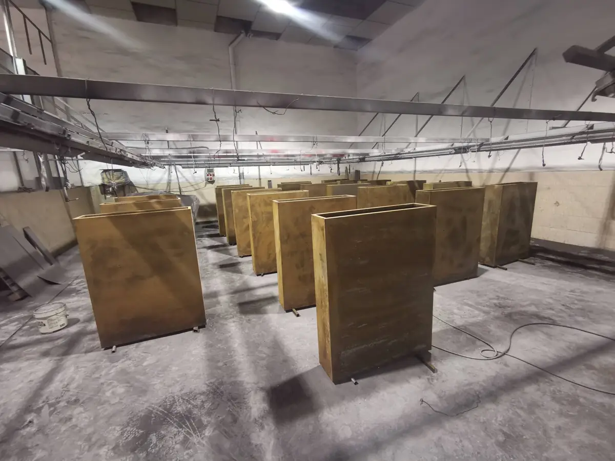 Pièces suspendues dans la cabine de thermolaquage Pilonatic